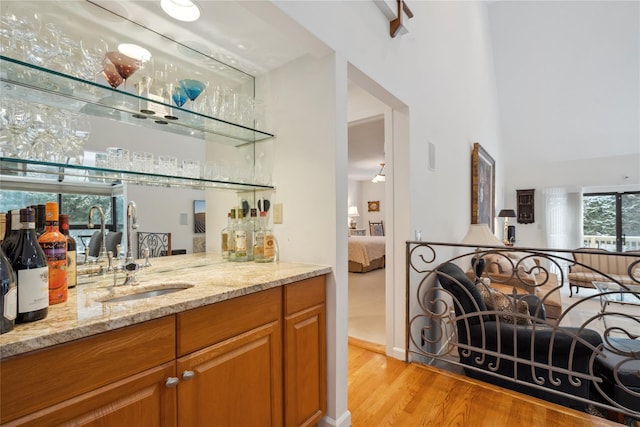 bar with light stone countertops, sink, and light hardwood / wood-style flooring