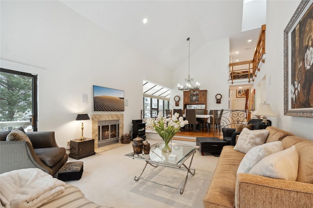 carpeted living room featuring a wealth of natural light, a fireplace, high vaulted ceiling, and an inviting chandelier