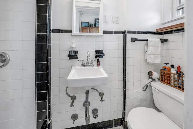 bathroom featuring sink, tiled shower, toilet, and tile walls