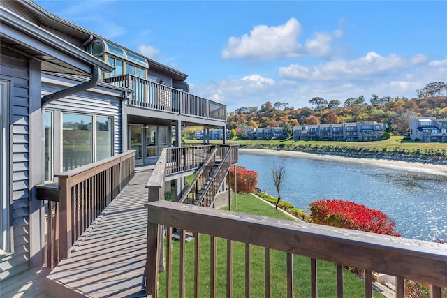 wooden deck featuring a lawn and a water view