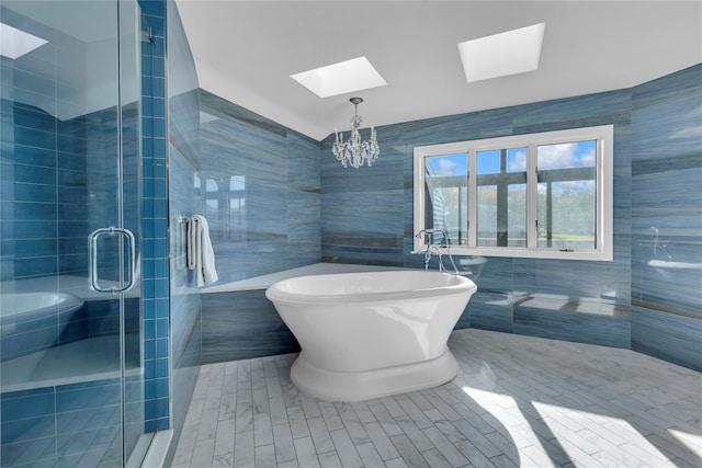 bathroom with shower with separate bathtub, a skylight, tile walls, and a notable chandelier