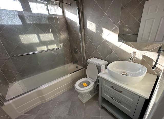 full bathroom featuring tile patterned floors, toilet, vanity, tile walls, and tiled shower / bath