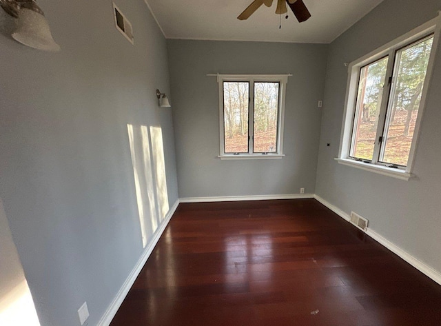 empty room featuring dark hardwood / wood-style flooring, ceiling fan, and plenty of natural light