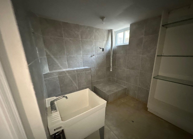 bathroom featuring a tile shower, tile walls, and sink