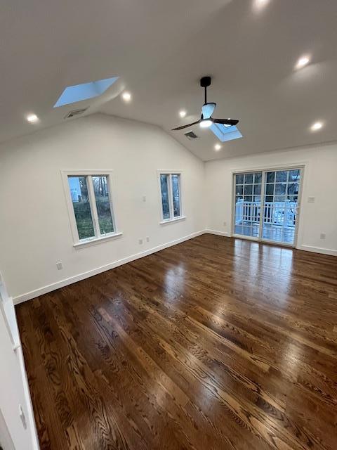 interior space featuring vaulted ceiling with skylight, ceiling fan, and dark wood-type flooring