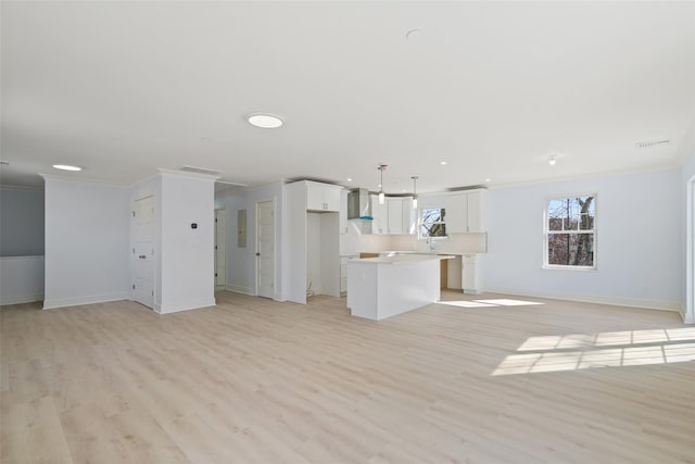 unfurnished living room featuring ornamental molding, visible vents, light wood-style floors, and baseboards