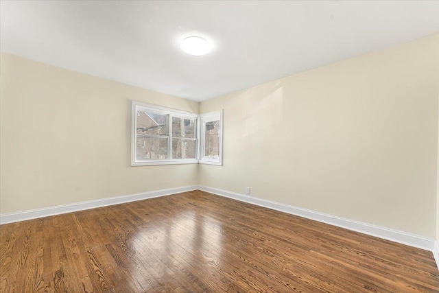 spare room featuring baseboards and dark wood-style flooring