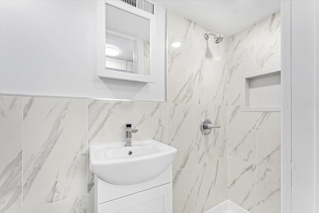 full bath with tile walls, vanity, and a tile shower