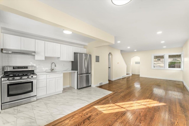 kitchen with sink, stainless steel appliances, white cabinetry, and range hood