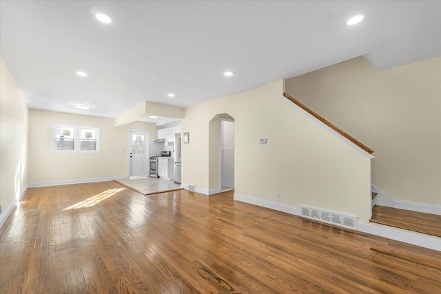 unfurnished living room with visible vents, recessed lighting, stairway, wood-type flooring, and baseboards