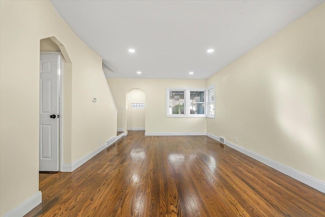 spare room with recessed lighting, baseboards, wood-type flooring, and arched walkways