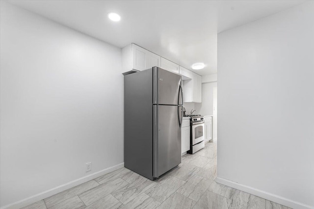 kitchen with baseboards, appliances with stainless steel finishes, light countertops, and white cabinetry