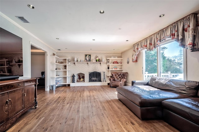 living room with hardwood / wood-style flooring, a brick fireplace, and ornamental molding