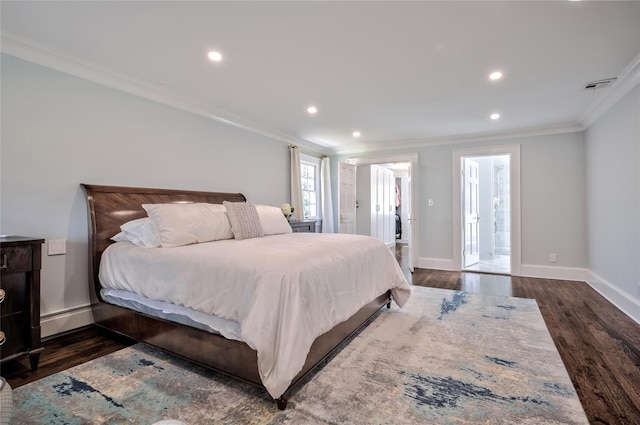 bedroom featuring ornamental molding, connected bathroom, baseboard heating, and dark wood-type flooring