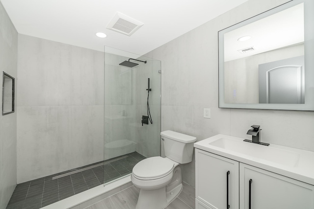 bathroom featuring a tile shower, vanity, and toilet