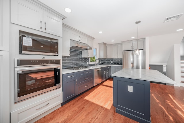 kitchen featuring appliances with stainless steel finishes, light wood-type flooring, gray cabinetry, sink, and a kitchen island