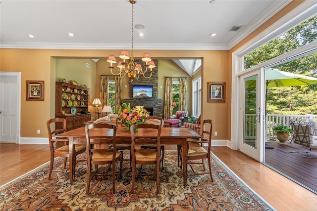 dining room with crown molding, an inviting chandelier, a brick fireplace, and hardwood / wood-style flooring