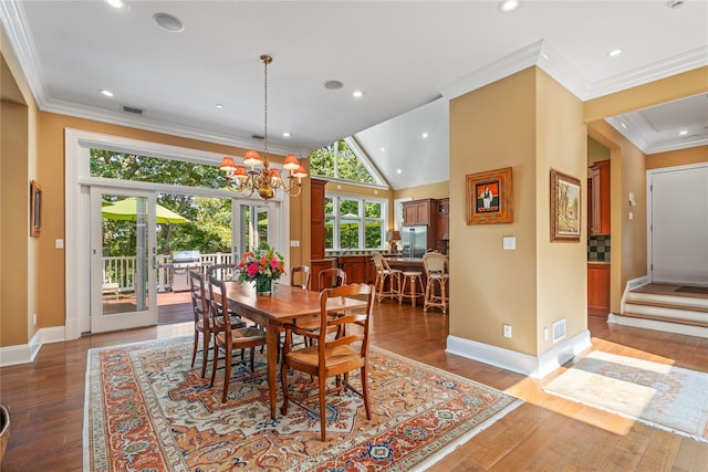 dining area featuring a notable chandelier, crown molding, vaulted ceiling, and light wood-type flooring