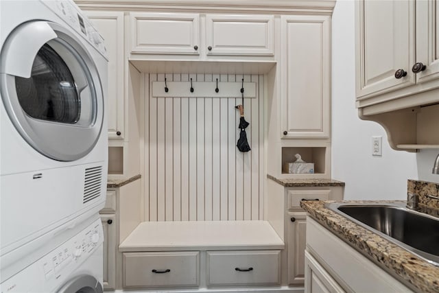 mudroom featuring stacked washer and dryer and sink