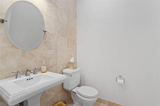 bathroom with tile walls, sink, and toilet