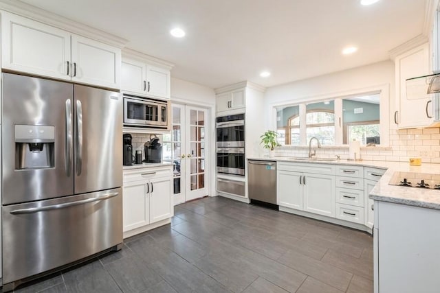 kitchen featuring tasteful backsplash, sink, white cabinets, and appliances with stainless steel finishes