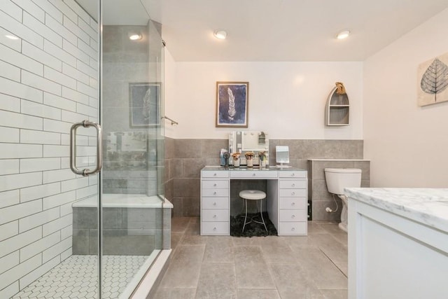 bathroom with tile patterned flooring, vanity, a shower with shower door, and toilet