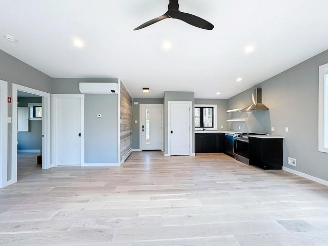 kitchen with an AC wall unit, wall chimney exhaust hood, ceiling fan, light wood-type flooring, and range