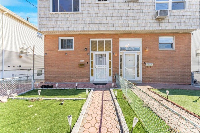 entrance to property with a yard, fence, mansard roof, and brick siding