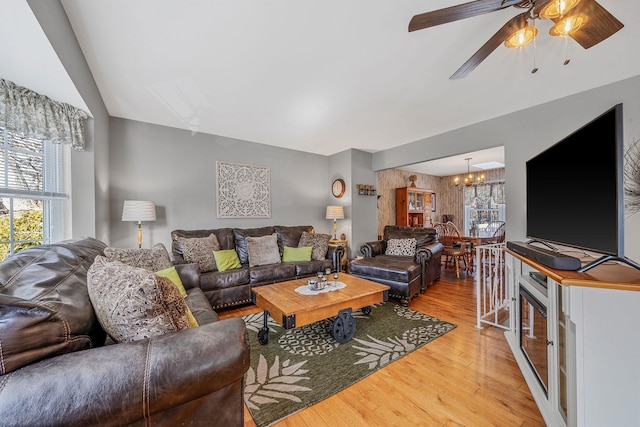 living room featuring ceiling fan with notable chandelier and hardwood / wood-style flooring