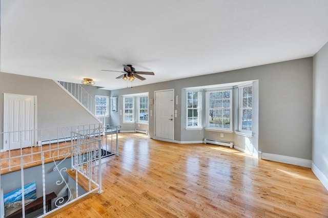 unfurnished living room with baseboard heating, wood finished floors, and baseboards