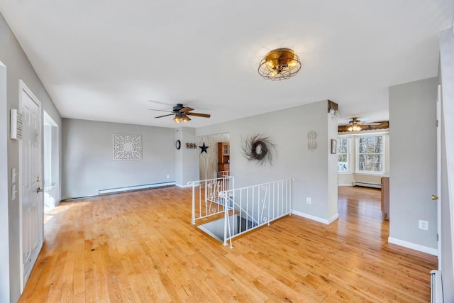 unfurnished room featuring light wood finished floors and baseboard heating