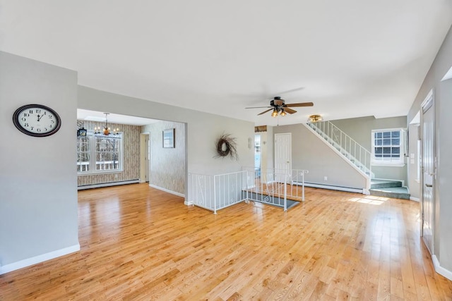 unfurnished living room with a baseboard heating unit, a baseboard radiator, plenty of natural light, and light wood-style flooring