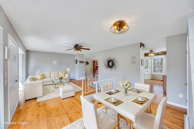 dining room with baseboards, a baseboard heating unit, ceiling fan, and wood finished floors