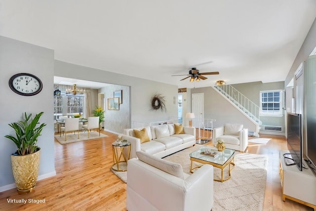 living area featuring light wood-type flooring, plenty of natural light, baseboards, and stairs