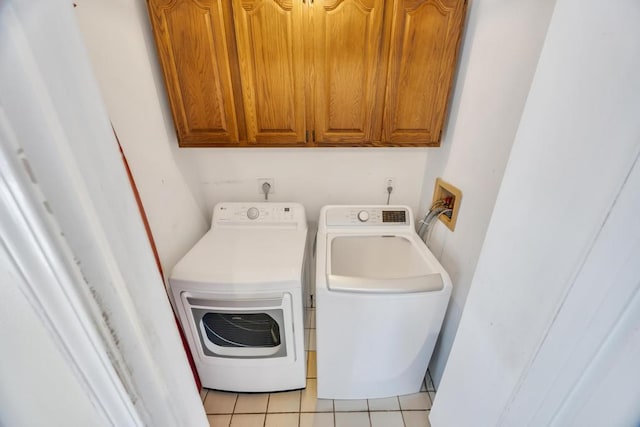 washroom featuring light tile patterned floors, washing machine and dryer, and cabinet space