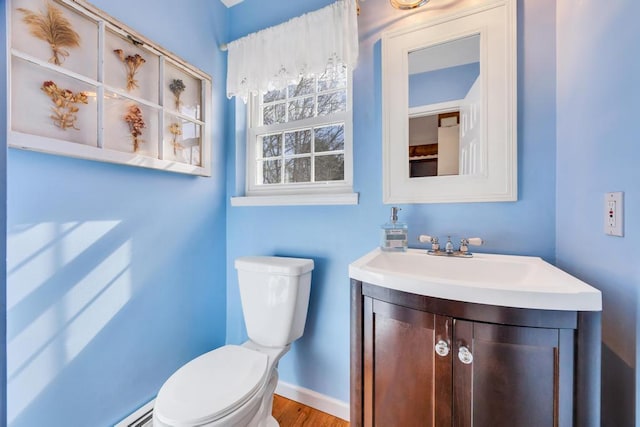 bathroom with a baseboard radiator, baseboards, vanity, and toilet