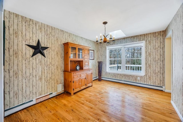 unfurnished dining area featuring a baseboard radiator, light wood-style floors, baseboard heating, wallpapered walls, and an inviting chandelier