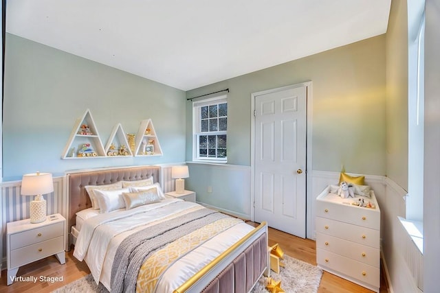 bedroom featuring light wood-style floors and a wainscoted wall