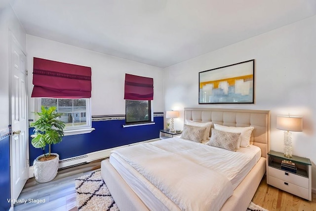 bedroom featuring a baseboard heating unit and wood finished floors