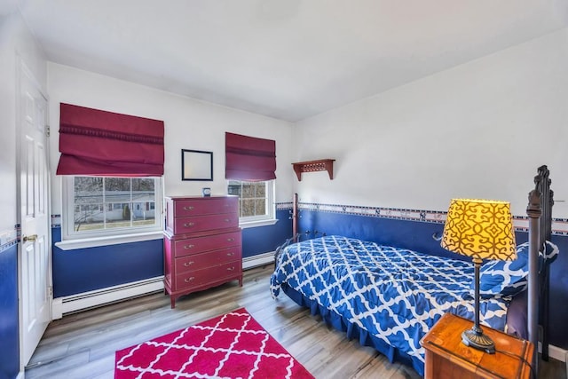 bedroom with baseboard heating and wood finished floors