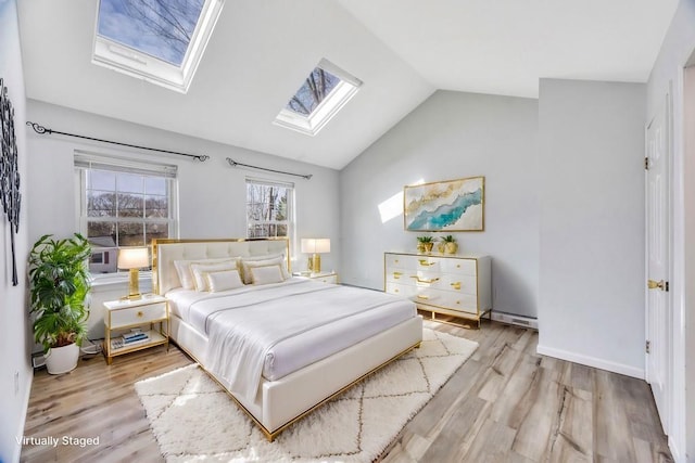 bedroom featuring vaulted ceiling with skylight, light wood finished floors, and baseboards