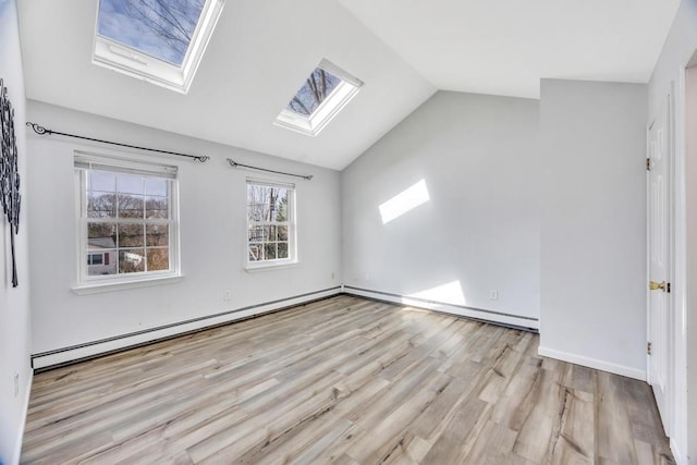 interior space featuring vaulted ceiling with skylight, light wood-style flooring, baseboards, and a baseboard radiator