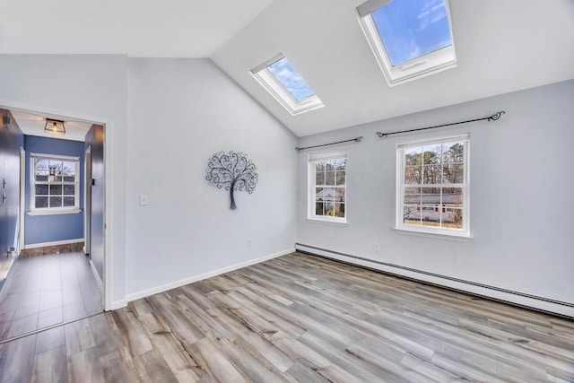 empty room with vaulted ceiling with skylight, baseboards, baseboard heating, and light wood-style flooring