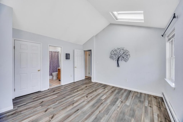 unfurnished bedroom with lofted ceiling with skylight, baseboards, baseboard heating, and light wood finished floors