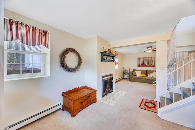 carpeted living room with a fireplace with flush hearth, ceiling fan, baseboard heating, and stairs