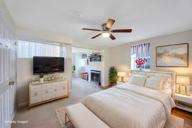 bedroom with a glass covered fireplace, ceiling fan, and baseboards