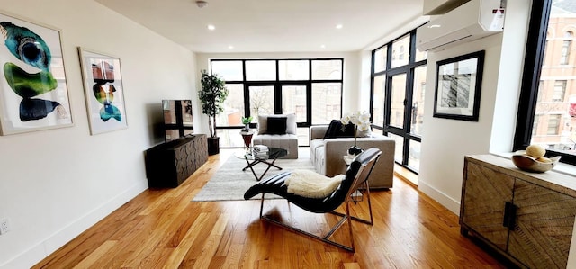 living area featuring light wood finished floors, recessed lighting, an AC wall unit, and baseboards