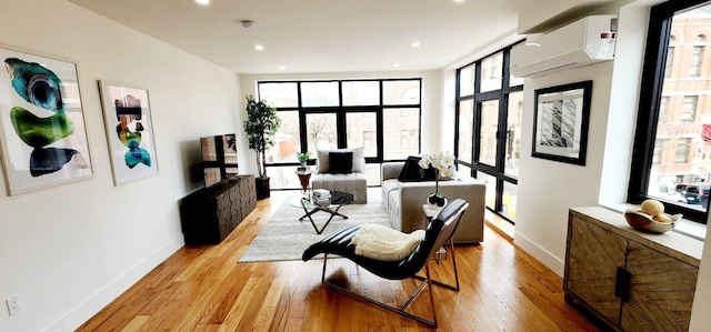 sitting room with recessed lighting, light wood-type flooring, baseboards, and an AC wall unit