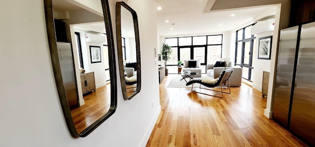 hallway featuring light wood-style flooring, recessed lighting, baseboards, and a wall mounted AC