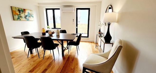 dining area with baseboards, light wood-type flooring, and a wall unit AC